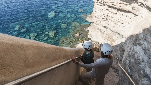 Visiteurs équipés admirant la vue depuis l'Escalier du Roy d'Aragon à Bonifacio